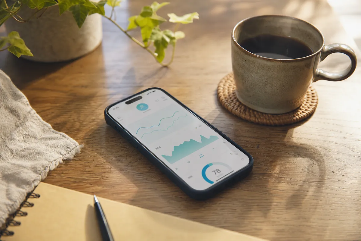 健康データのグラフが表示されたスマートフォンとコーヒーカップ