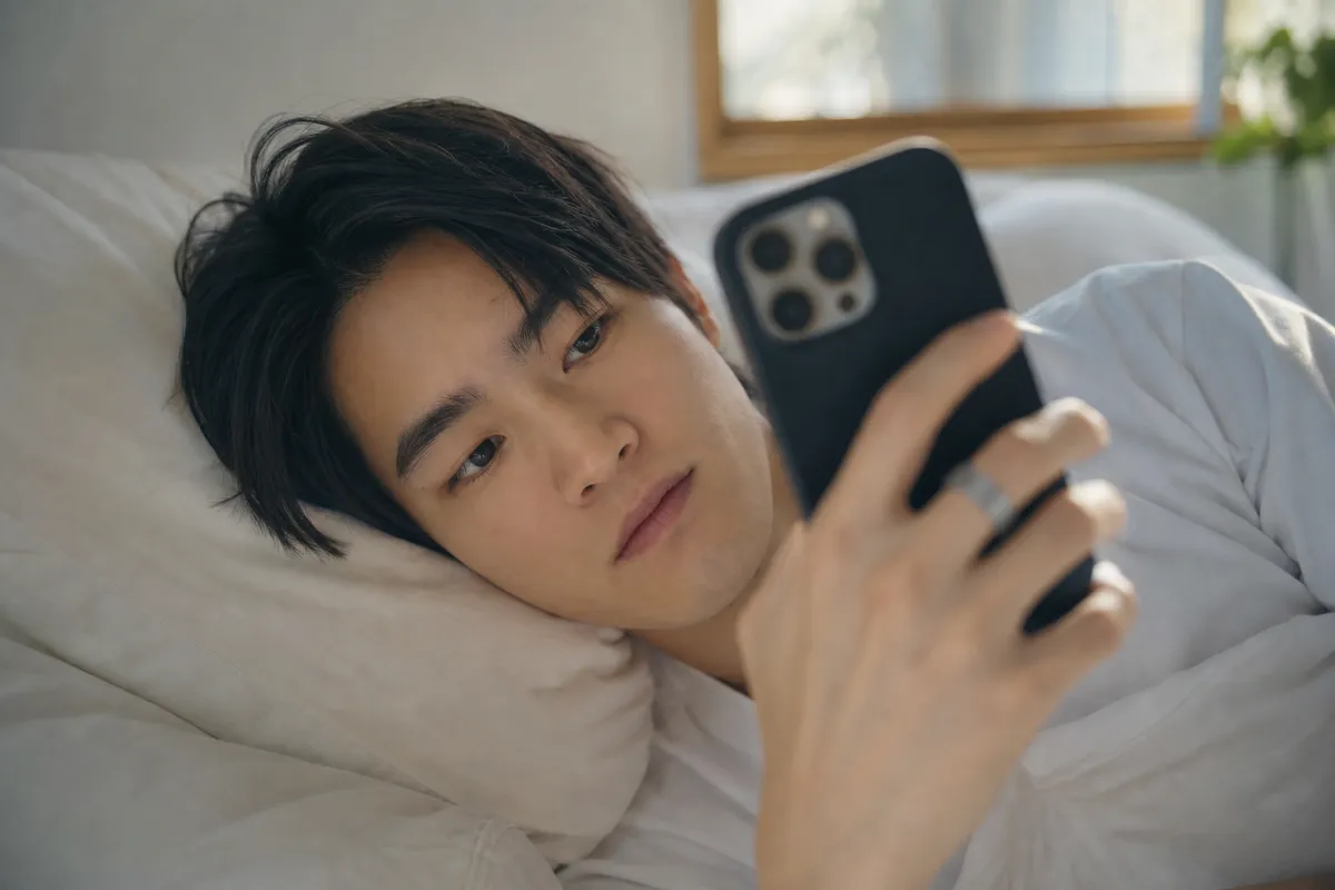 朝、スマートフォンで睡眠データを確認する人