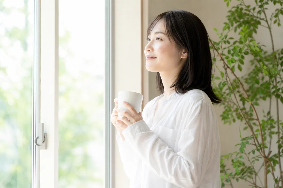穏やかな朝の光の中でリラックスした姿勢で立つ人物・前向きな日常の情景